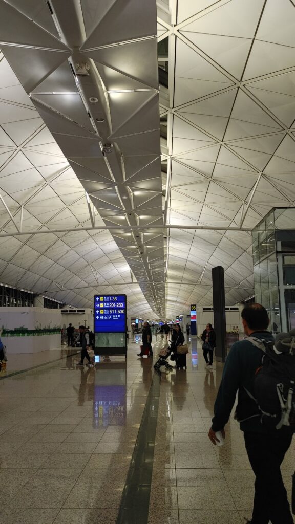 香港の空港。めちゃくちゃ広い。この廊下も先が見えず、まるで地球の反対側に続いているみたいデスネ…。